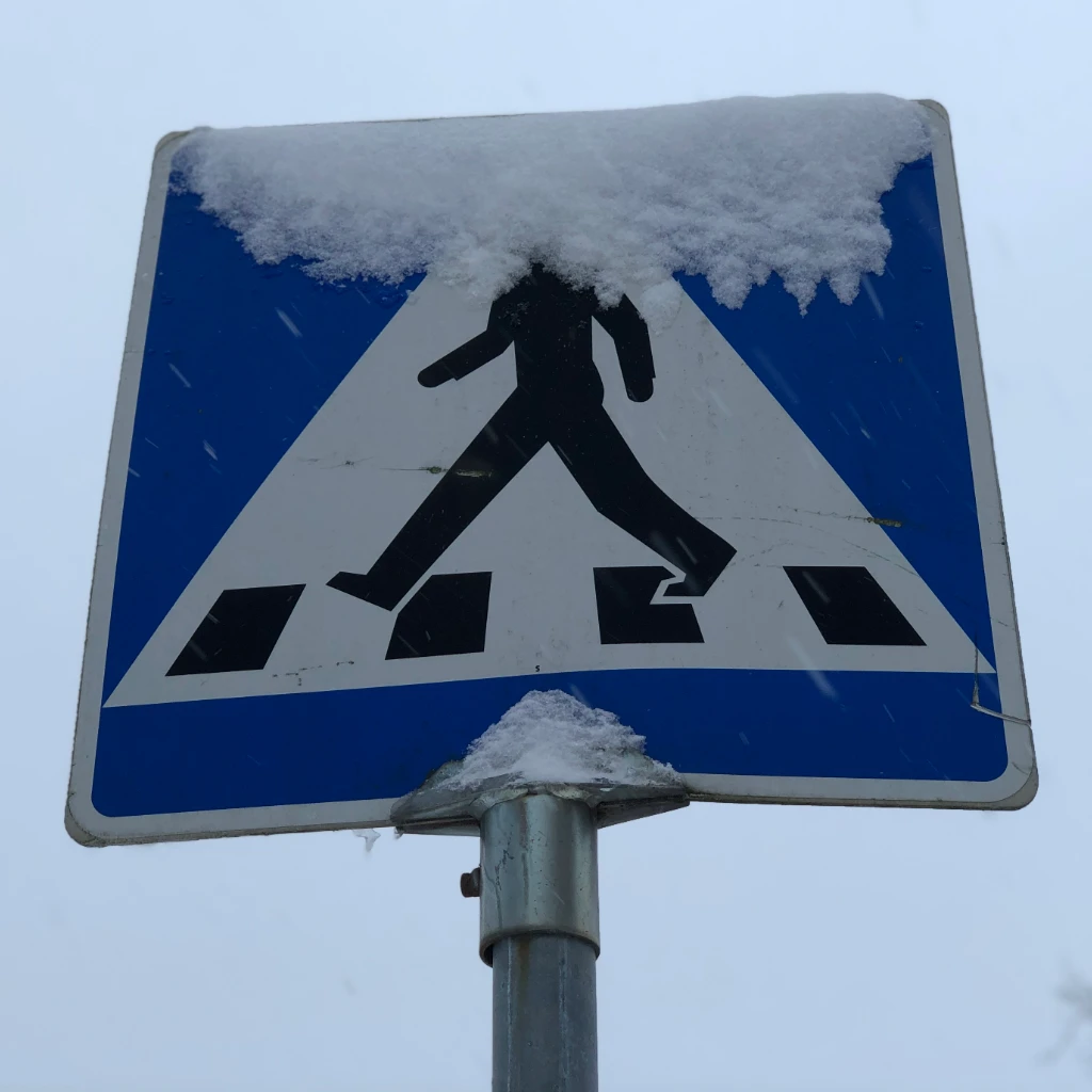 Crosswalk sign with snow covering man's head