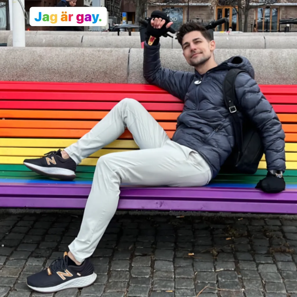 Jeremiah sitting on a rainbow colored public bench
