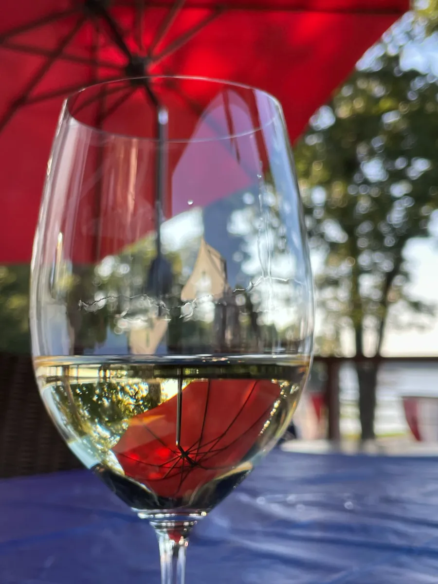 Glass of white wine with reflection of red sun shade