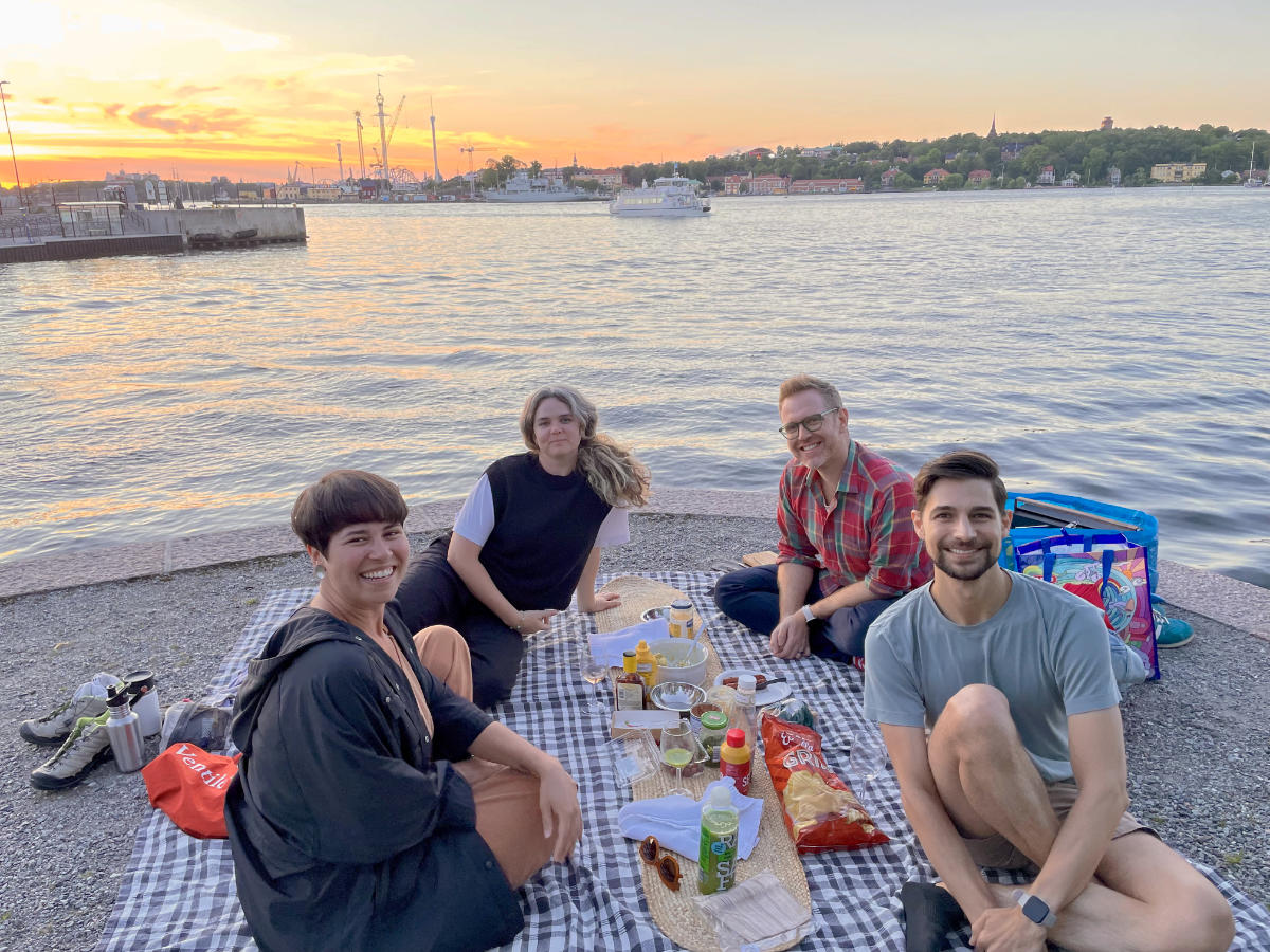 Friends sitting by waterway with summer sunset