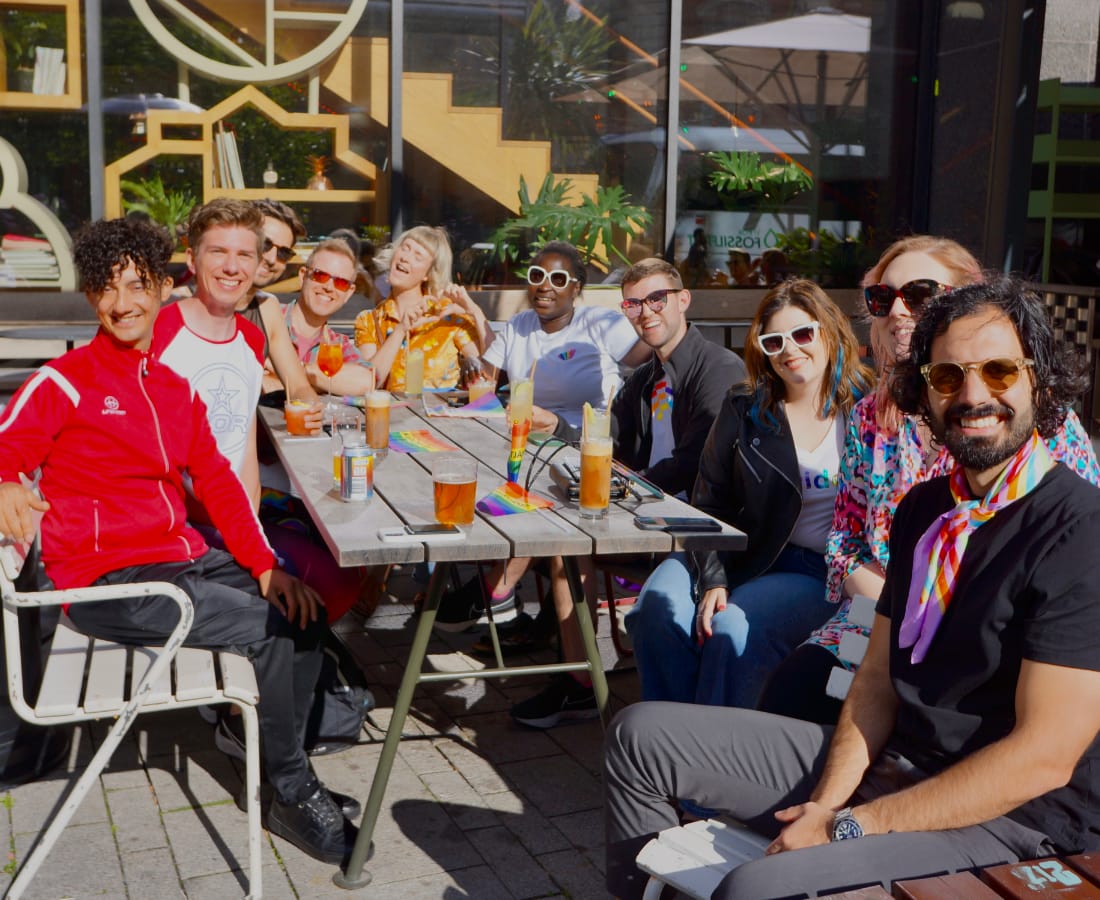 10 friends sitting at table outside on a sunny day with cocktails