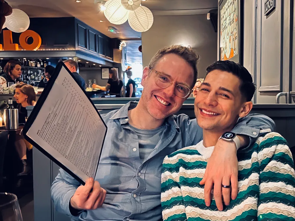 Arthur and Jeremiah sitting at restaurant embracing and smiling