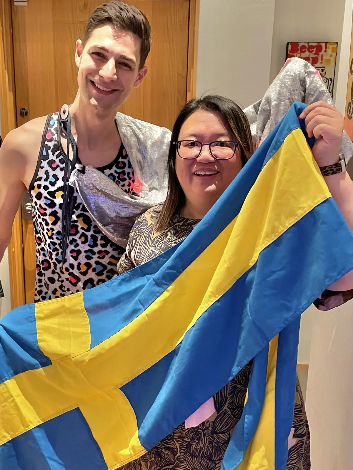 Jeremiah dressed in a rainbow cheetah print shirt and Vivien holding a Swedish flag