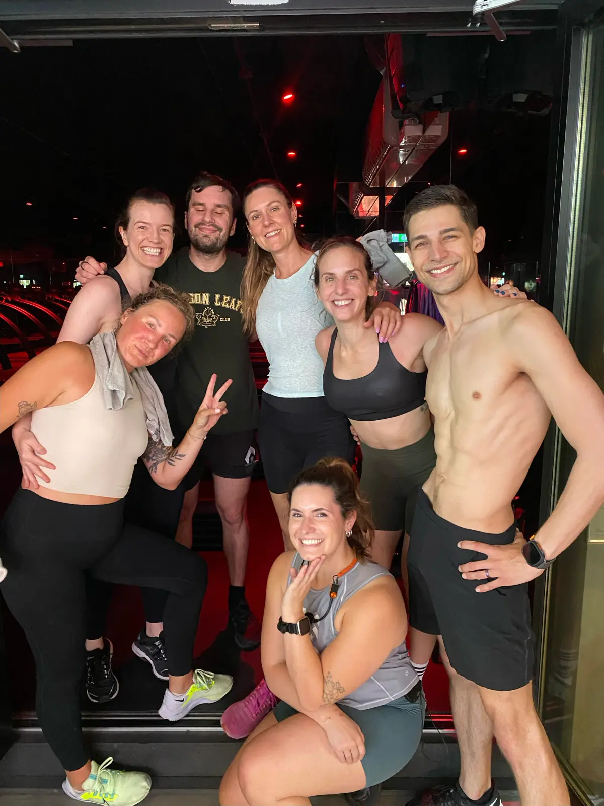 Group of fit people standing around Sophie after teaching her final Barry’s class
