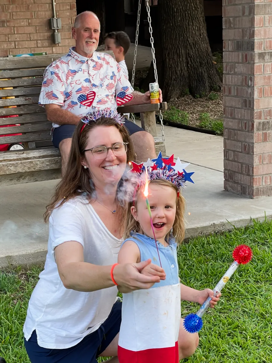 Adrienne helping P with a sparkler with Art sitting in the background