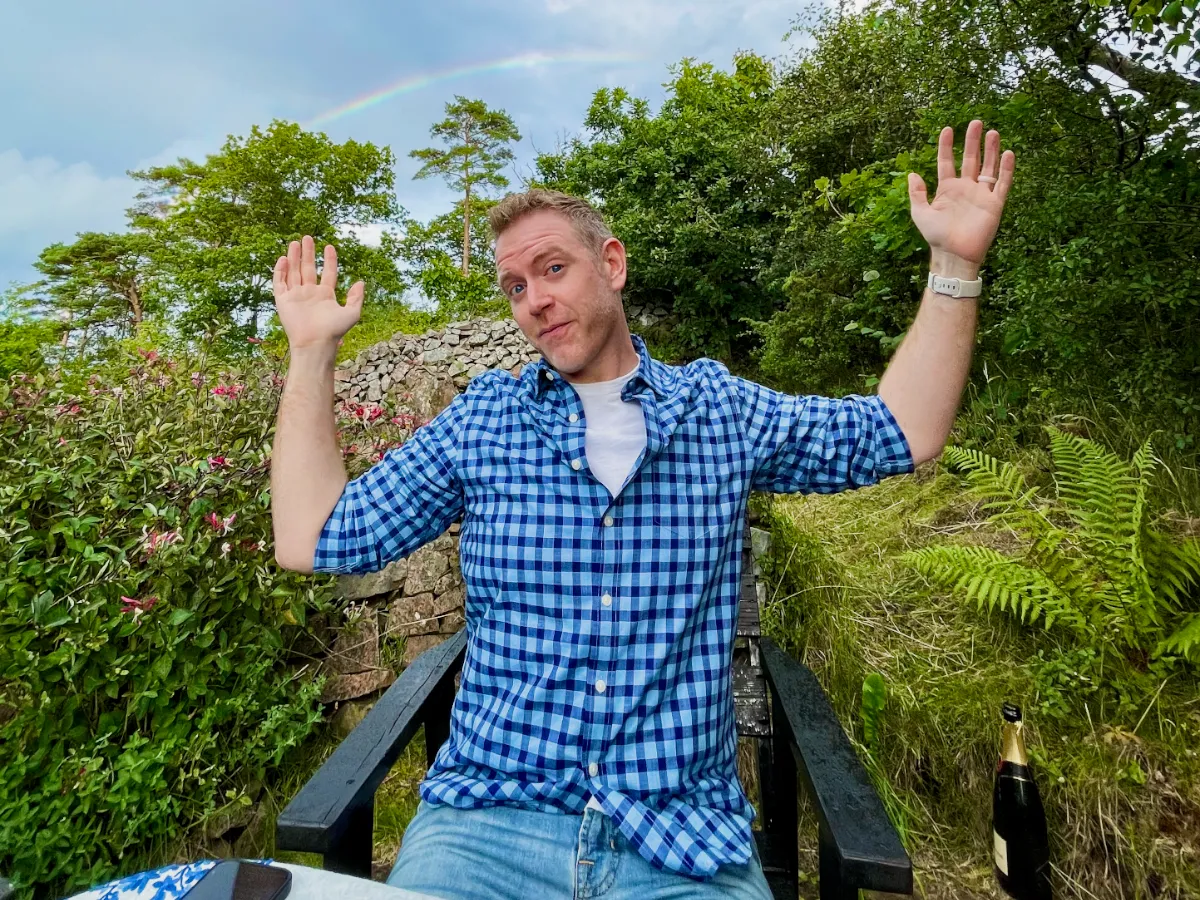 Arthur stretching his arms above his head with a rainbow stretching across a rainy sky behind him