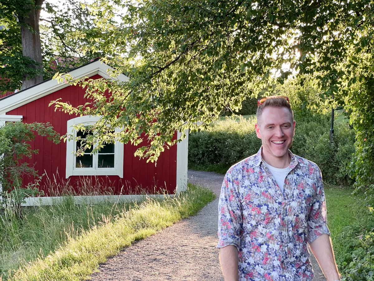 Arthur smiling while walking on a path with a red house in the background