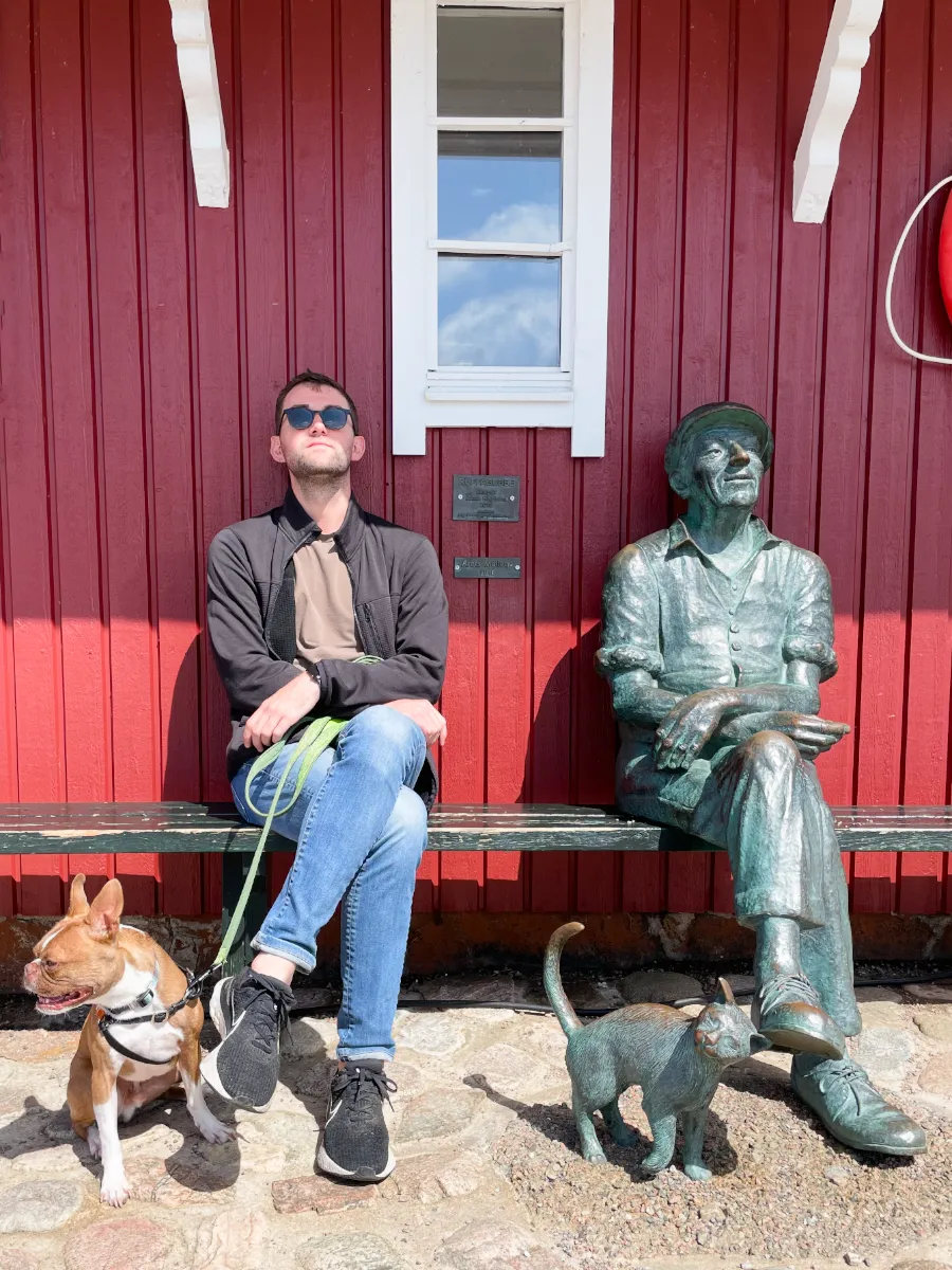 Wes and Finn on a leash sitting beside status sitting with a cat on a leash