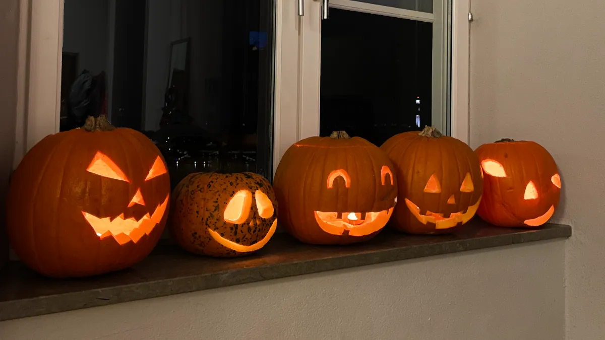 5 jack-o-lanterns sitting on the window sill