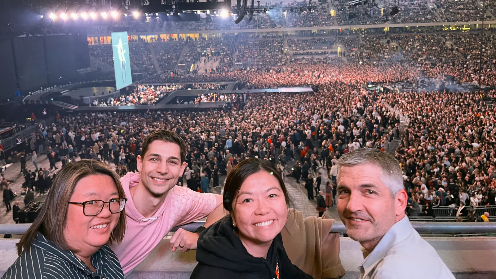 Vivien, Jeremiah, and friends in arena with stage behind them