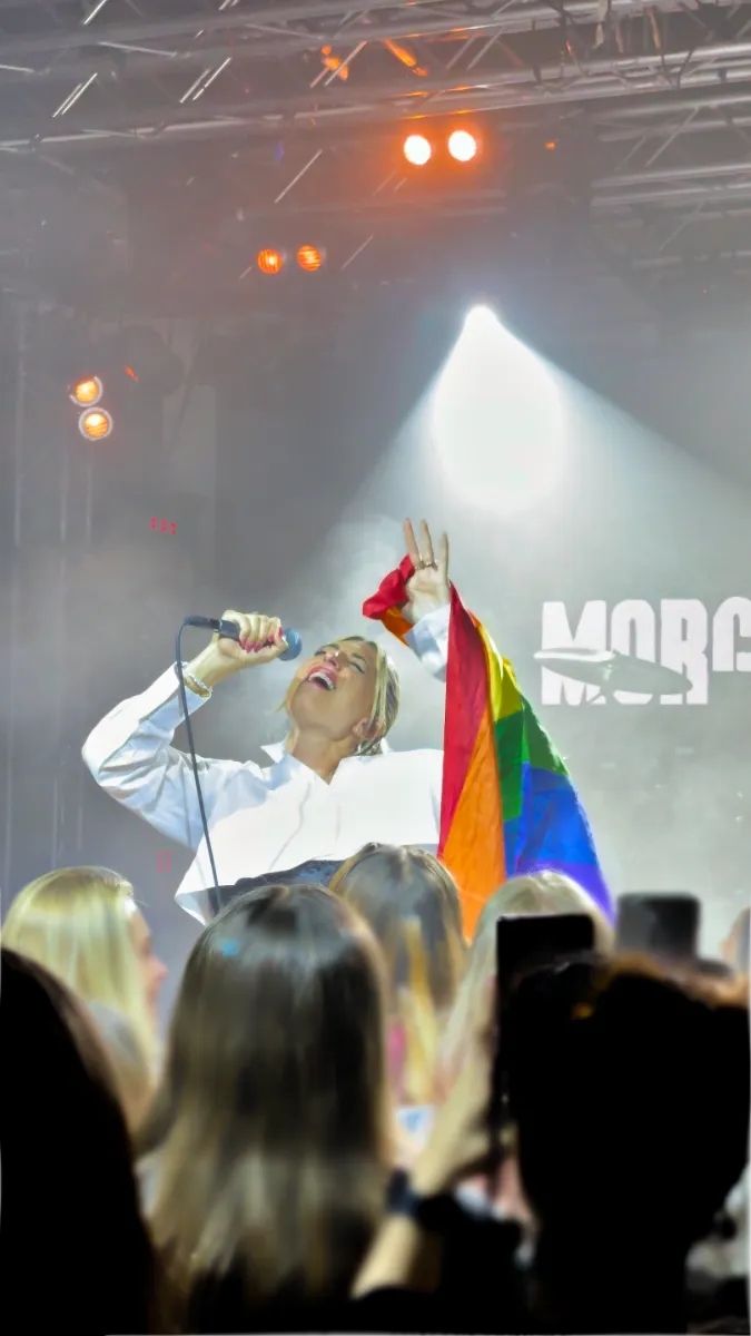 Morgan St Jean holding a Pride flag while singing