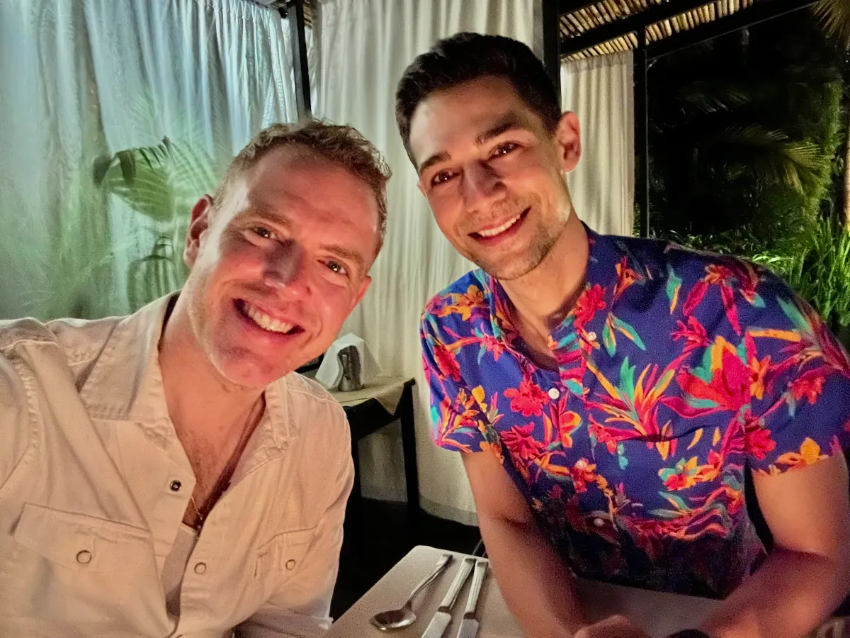 Arthur and Jeremiah at dinner. Jeremiah wears a brightly colored colored shirt with rainforest flower print