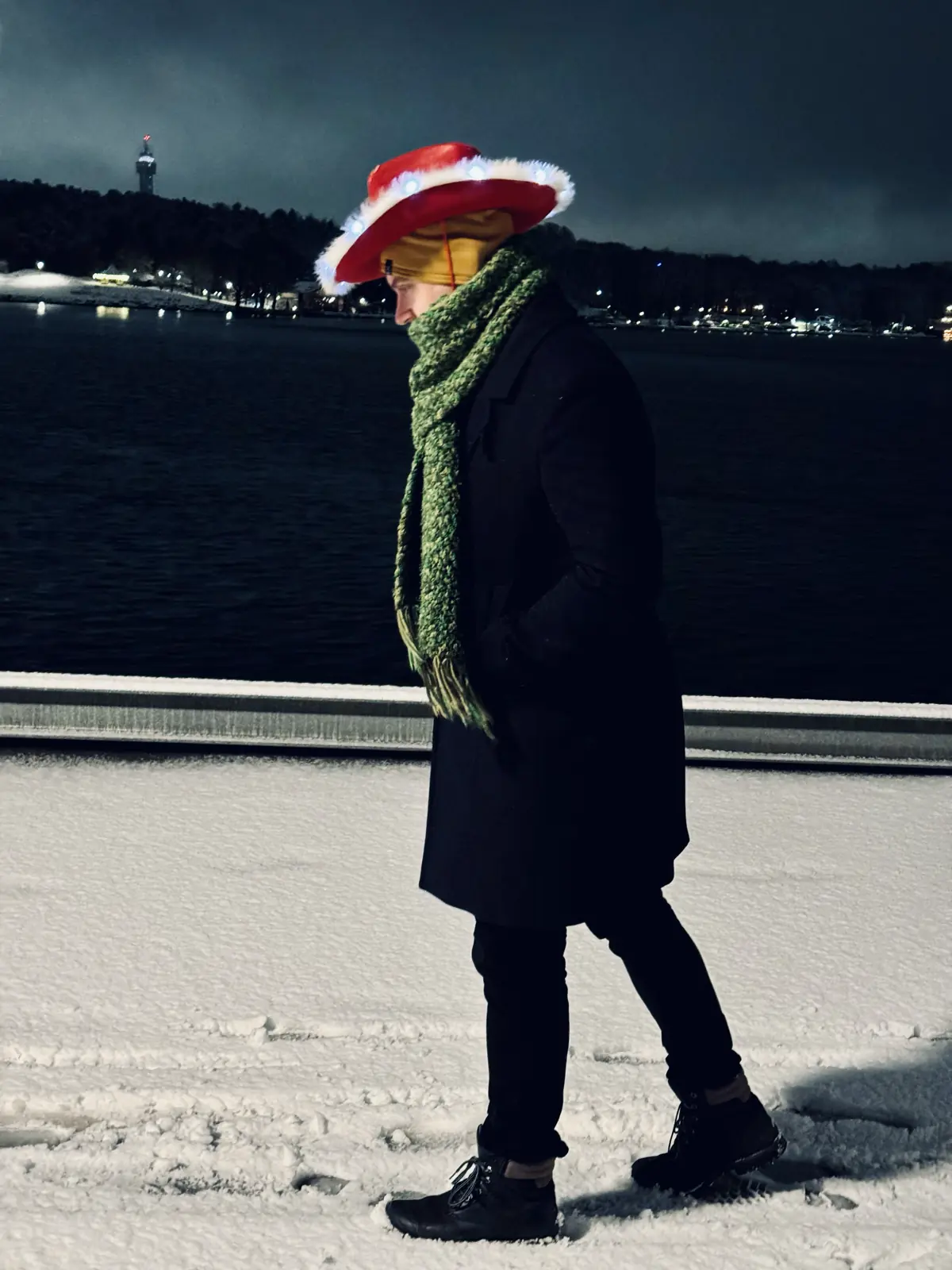 Arthur walking outside in snow wearing red cowbow hat with white fuzzy edges and lights