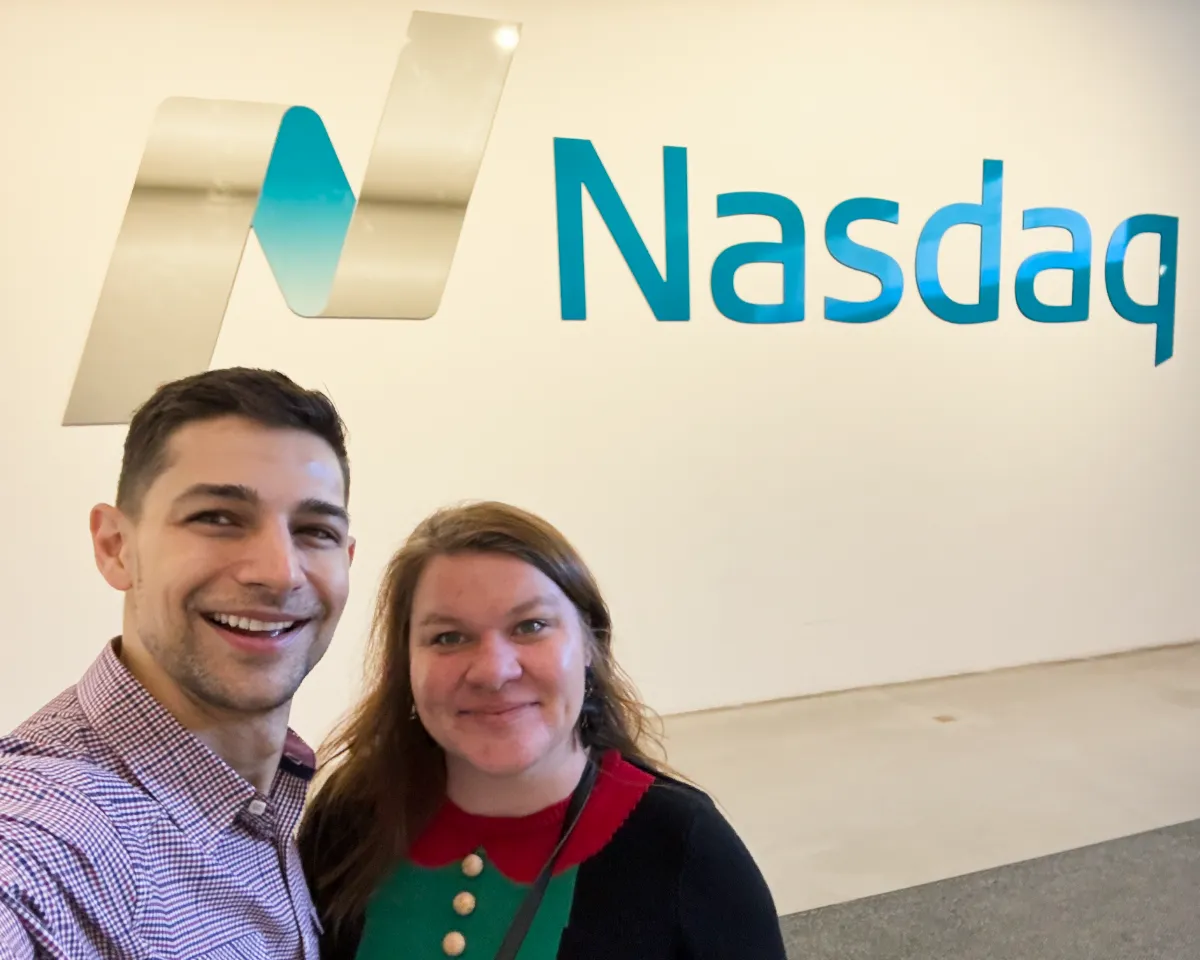 Jeremiah and Karin in front of Nasdaq sign in lobby