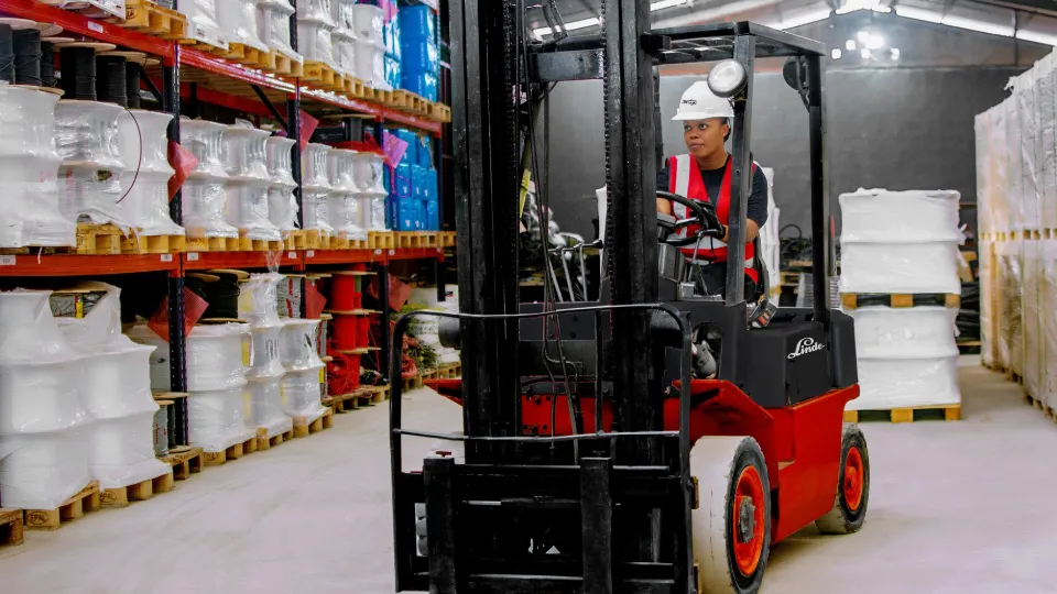 Woman driving electric forklift in warehouse